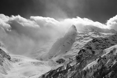 Glacier, snowy mountain peaks and sunlight cloudy sky. Caucasus Mountains at winter, region Dombay....
