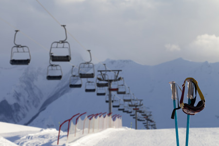 Snowy skiing slope, chair-lift and ski mask on ski poles in evening sunlight mountains. Caucasus Mountains at winter, Georgia, region Gudauri.の写真素材