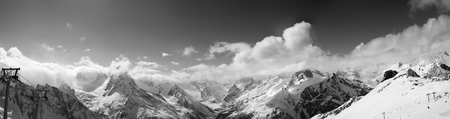 Black and white panorama of ski slope and snowy mountains in clouds. Caucasus Mountains in winter, region Dombay.の写真素材