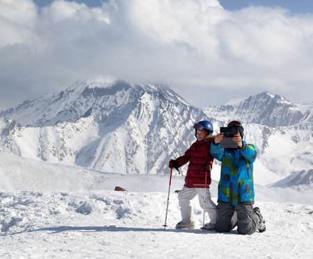 Happy little skier with father makes selfie on tablet device in sunlight snowy winter mountains. Caucasus Mountains, Georgia, region Gudauri.の写真素材