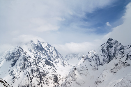 High mountain peaks covered with snow and beautiful blue sky with clouds at winter day. Caucasus Mountains, region Dombay.の写真素材