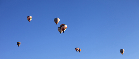 GOREM, CAPPADOCIA, TURKEY - MAY 07, 2013: Panoramic view on multicolor hot air balloons on blue clear sunlight sky at early morning. View from distance.のeditorial素材