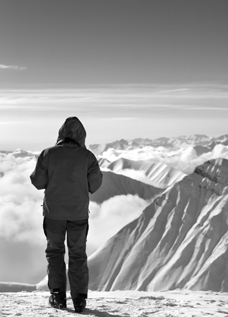 Skier on top of snowy mountains in clouds at nice sun day. Caucasus Mountains, Georgia, region Gudauri in winter. Black and white toned landscape.の写真素材