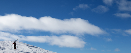 Blue sky and skier with skis on his shoulder go up to top of mountain. Caucasus Mountains in winter, Georgia, region Gudauri, Mount Kudebi. Panoramic view.の写真素材