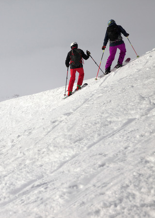 Skiers on snowy freeride slope and overcast misty sky at day with bad weather before blizzard. Caucasus Mountains in winter, Georgia, region Gudauri.の写真素材
