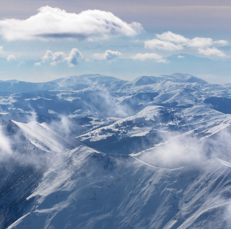 Snowy sunlight mountains in haze and cloudy sky. Caucasus Mountains, Georgia, region Gudauri at winter.の写真素材
