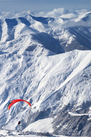 Paragliding at snowy mountains over ski resort at sunny day. Caucasus Mountains. Georgia, region Gudauri.の写真素材