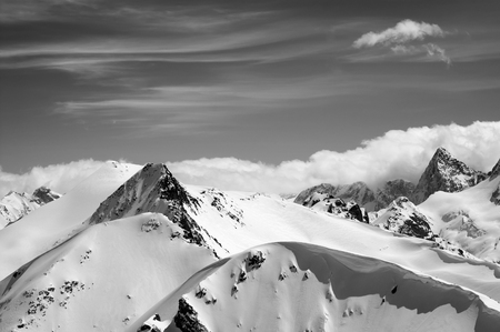 Winter mountains with snow cornice and sky with clouds in nice winter day. Caucasus Mountains, region Dombay. View from the top of mount Musa Achitara. Black and white toned landscape.

の写真素材