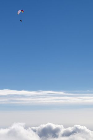 Blue sky with sunlight clouds and silhouette of paraglider at sunny winter dayの写真素材
