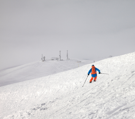 Skier descent on snowy freeride slope and overcast misty sky at day with bad weather before blizzard. Caucasus Mountains in winter, Georgia, region Gudauri.の写真素材