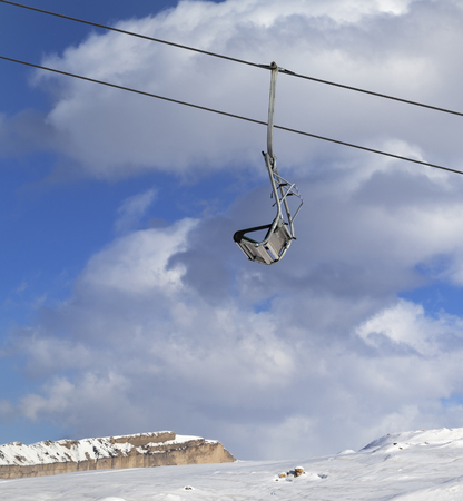 Snowy slope, ski-lift and blue sky with clouds at sunny winter dayの写真素材