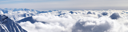 Panorama of snowy mountains covered with beautiful sunlight clouds at sunny winter evening. Caucasus Mountains, Georgia, region Gudauri.の写真素材