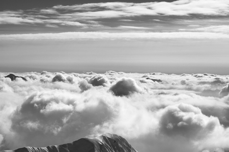 Snowy mountains covered with beautiful sunlight clouds at sunny winter evening. Caucasus Mountains, Georgia, region Gudauri. Black and white toned landscape.の写真素材
