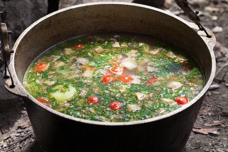 Freshly cooked hot soup in sooty cauldron on camp fire. Outdoor camping cooking.の写真素材