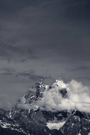 High mountains in clouds. Caucasus Mountains, Georgia, region Svaneti, Mount Ushba. Black and white toned landscape.の写真素材