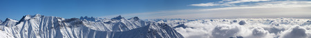 Large panorama of snowy mountains covered with beautiful sunlight clouds at sunny winter day. Caucasus Mountains, Georgia, region Gudauri.の写真素材