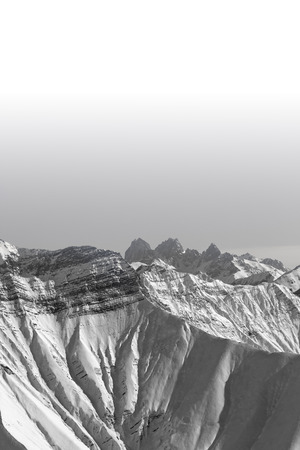High rocky mountains in snow and clear sky at sun winter day. Caucasus Mountains, Georgia, region Gudauri. Black and white toned landscape with copy space.の写真素材