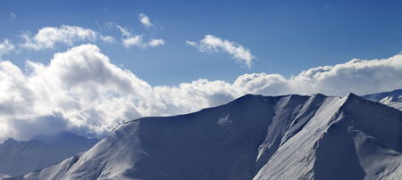 Panoramic view on snowy off piste slope and sunlit sky with clouds in evening. Georgia, region Gudauri. Caucasus Mountains in winter.の写真素材