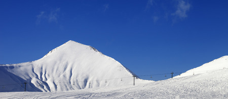 Panoramic view on snowy ski slope with ropeway at sunny winter day. Caucasus Mountains. Georgia, region Gudauri.の写真素材