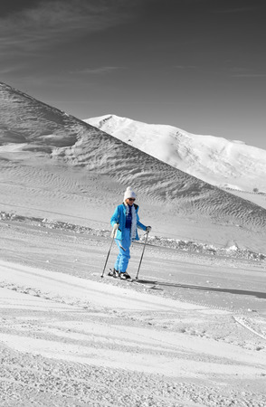 Black and white winter mountains and skier in blue on snowy ski slope at nice sun day. Caucasus Mountains, Shahdagh, Azerbaijan. Selective color effect.の写真素材
