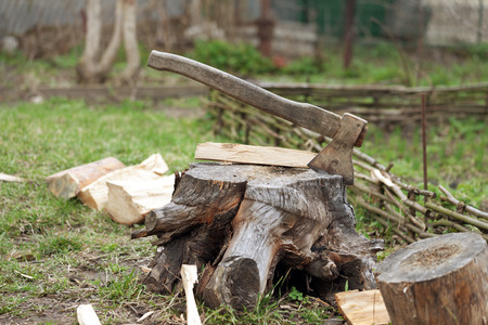 Old axe in tree stump on cottage glade at summer dayの写真素材