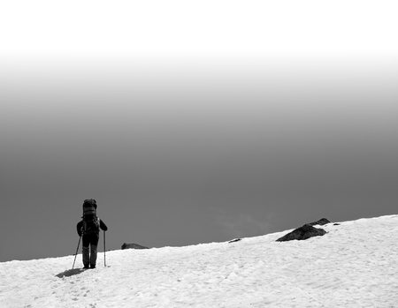 Hiker with big backpack in snowy mountains. Black and white toned landscape with copy space.の写真素材