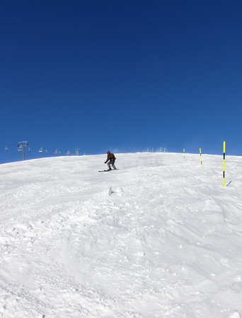 Skier downhill on snowy ski slope in sunny winter day. Caucasus Mountains, Georgia, region Gudauri. Wide angle view.の写真素材