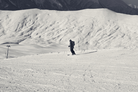 Skier downhill on snowy ski slope in sun winter evening. Caucasus Mountains, Georgia, region Gudauri. Black and white retro toned landscape.の写真素材