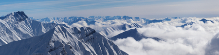 Panoramic view of snowy mountains covered with sunlit clouds at sunny winter day. Caucasus Mountains, Georgia, region Gudauri.の写真素材