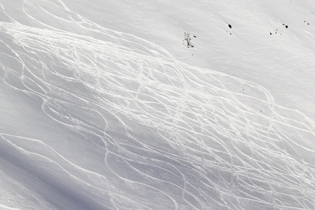 Snowy off-piste ski slope with traces from skis and snowboards at sunny winter dayの写真素材