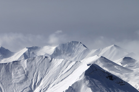 Snowy winter mountains in haze and cloudy sky at gray day. Caucasus Mountains, Georgia, region Gudauri.の写真素材