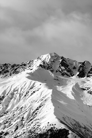 Black and white view on snow sunlit mountain and cloudy sky at winter evening. Caucasus Mountains. Svaneti region of Georgia.の写真素材