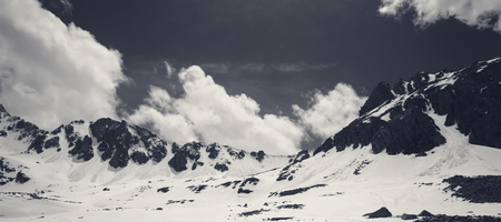 Panoramic view on snowy sunlit plateau with stones and cloudy sky at spring. Turkey, Kachkar Mountains, highest part of Pontic Mountains. Black and white retro toned landscape.の写真素材