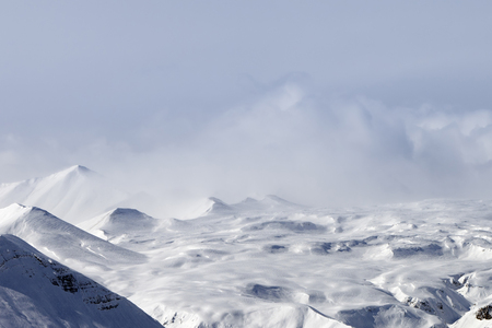 Snowy plateau at high mountains in fog and cloudy sky. Caucasus Mountains, Georgia, region Gudauri at winter.の写真素材