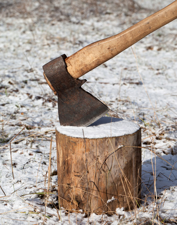 Axe and log in winter forest at sun day. Close-up view.の写真素材