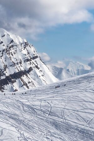 Snowy off-piste slope for freeriding with traces from skis, snowboards and silhouette of freeriders at sunny winter day. Caucasus Mountains, Georgia, region Gudauri.の写真素材