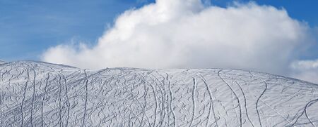 Panoramic view on snowy off-piste slope for freeride with traces from skis, snowboards and beautiful sky with clouds at sun winter morning.の写真素材