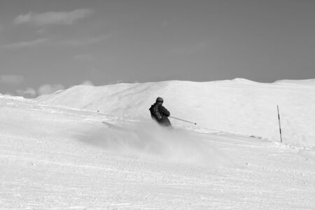Skier downhill on snowy ski slope in sun winter day. Caucasus Mountains, Georgia, region Gudauri. Black and white toned landscape.の写真素材