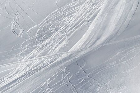 View on snowy off piste slope with traces of skis and snowboards in sun winter dayの写真素材