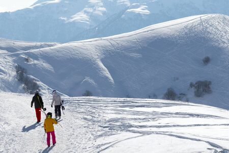 Skiers and snowboarders on snowy road at sun winter morning. Caucasus Mountains, Georgia, region Gudauri.の写真素材