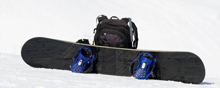 Snowboard and black backpack on ski slope in snow winter mountains at nice sunny day.の写真素材
