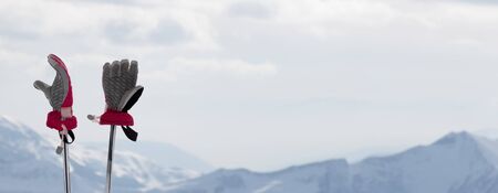 Ladies gloves on ski poles and snowy winter mountains in background. Caucasus Mountains. Georgia, region Gudauri. Panoramic view.の写真素材