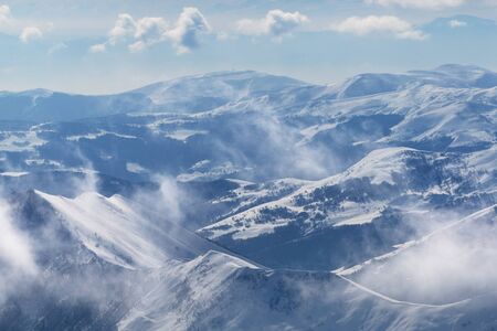 Snowy sunlight mountains in fog and multicolor cloudy sky. Caucasus Mountains, Georgia, region Gudauri at winter.の写真素材