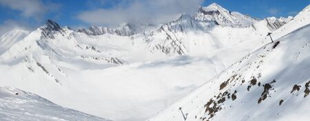 Panoramic view on snowy freeride trace and mountains in clouds at sun cold day. Caucasus Mountains in winter, Georgia, region Gudauri.の写真素材