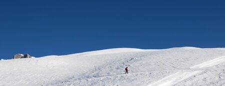 Snowboarder downhill on snowy slope in cold sun winter day. Caucasus Mountains, Georgia, region Gudauri. Panoramic view.の写真素材