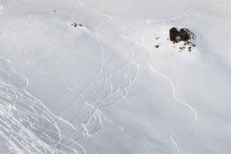 View on snowy off piste slope with traces of skis and snowboards at sunny winter dayの写真素材