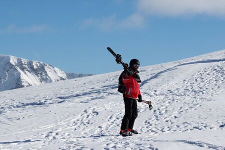 Skier with skis on his shoulder go up to top of snowy mountain in nice sun day. Caucasus Mountains in winter. Georgia, region Gudauri, Mount Kudebi.の写真素材