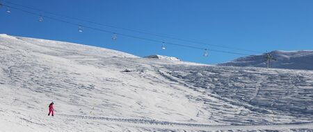 Snowboarder downhill on snowy ski slope at cold sun morning. Georgia, region Gudauri. Caucasus Mountains in winter. Panoramic view.の写真素材