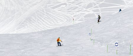 Skiers and snowboarders downhill on snowy ski trace at sun cold day. Caucasus Mountains in winter, Georgia, region Gudauri, mount Kudebi. Panoramic view.の写真素材