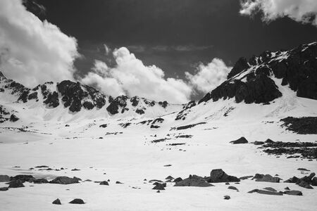 Snowy sunlit plateau with stones and cloudy sky at spring. Turkey, Kachkar Mountains, highest part of Pontic Mountains. Black and white toned landscape.の写真素材